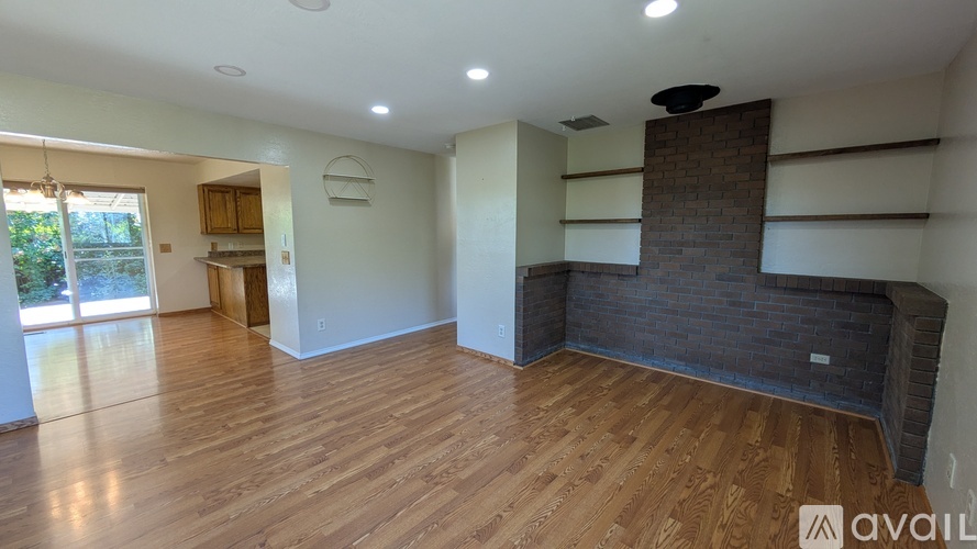 A spacious living room with wooden flooring and a brick fireplace.