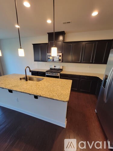 A kitchen with a granite countertop and black cabinets.