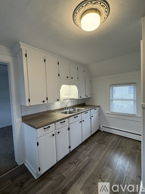 A kitchen with white cabinets and a wooden floor.
