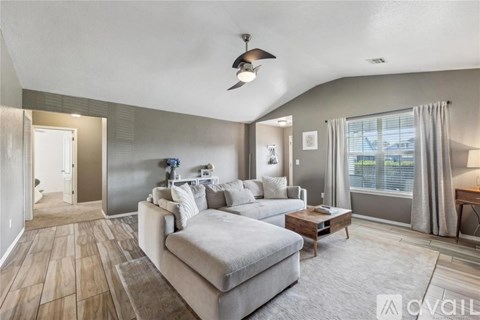 A spacious living room with a grey sofa and a wooden floor.