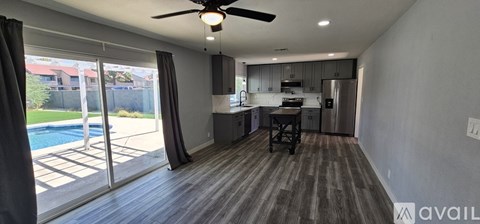 A modern kitchen with a dining table and a ceiling fan.