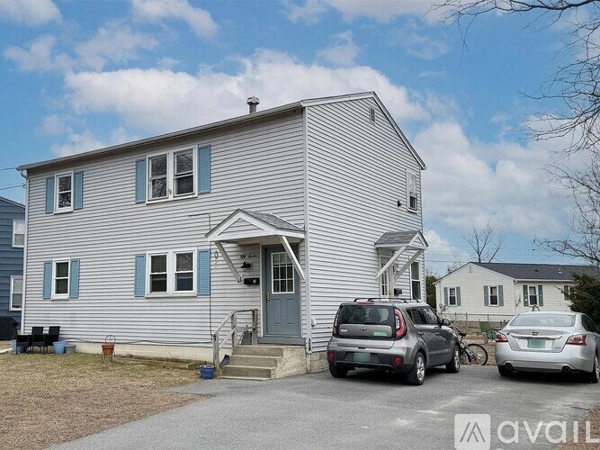 A house with a grey and blue exterior has a car parked in front of it.