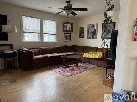 A living room with a brown couch and a ceiling fan.