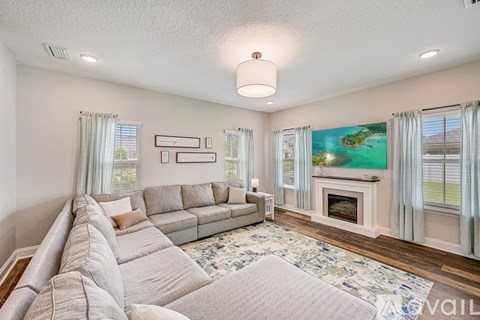 A living room with a grey sofa and a fireplace.