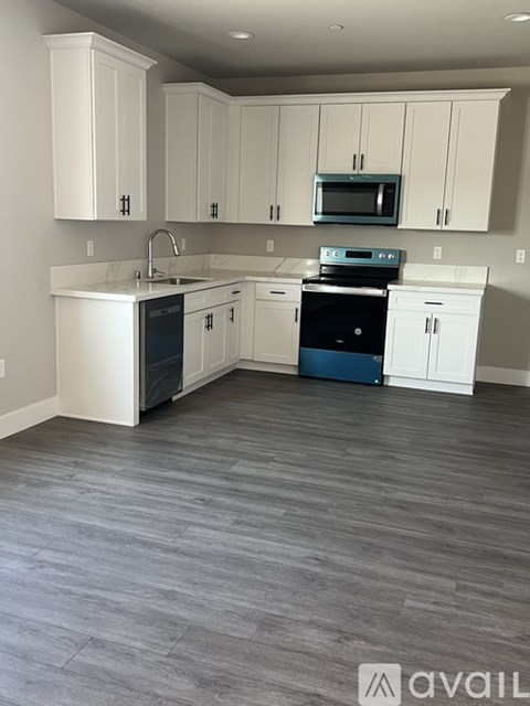 A kitchen with white cabinets and a grey floor.