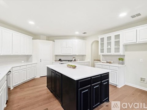 A kitchen with white cabinets and a black island.