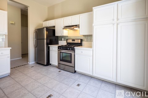 A kitchen with white cabinets and a black fridge.