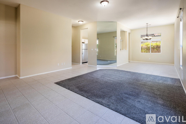 A spacious room with a rug on the floor and a door in the background.