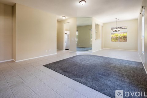 A spacious room with a rug on the floor and a door in the background.
