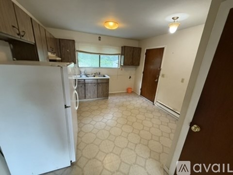 A kitchen with a white refrigerator and a tiled floor.