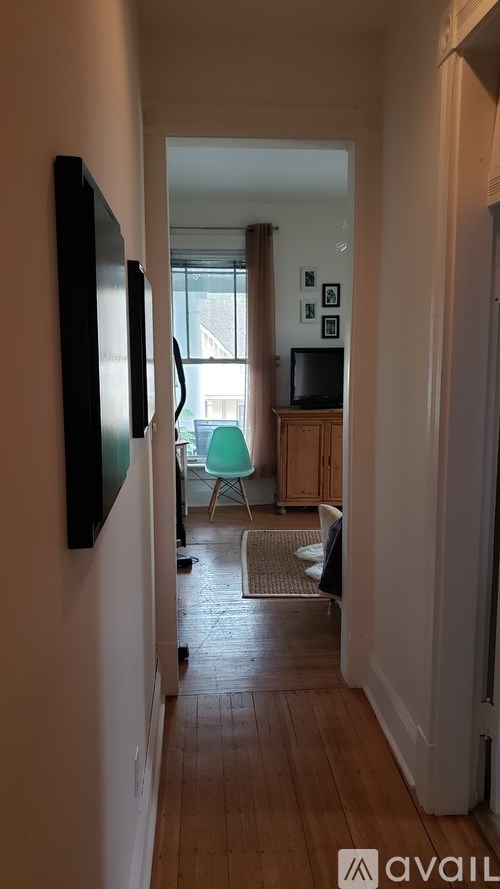 A hallway with a TV on the wall and a chair in the background.