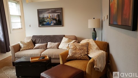 A living room with a couch, chair, and a painting on the wall.
