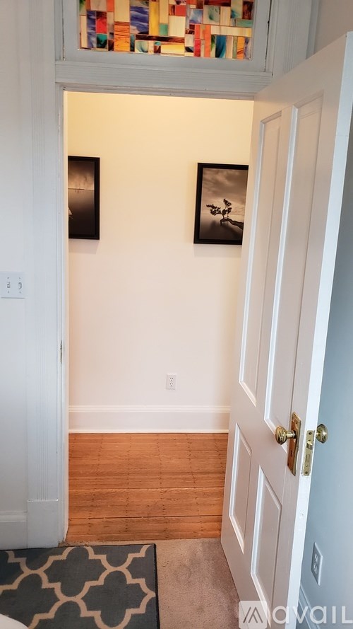 A hallway with a white door and two pictures on the wall.