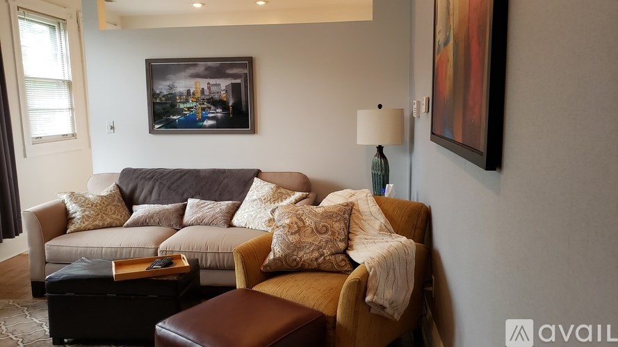 A living room with a brown leather chair and a grey couch with pillows.