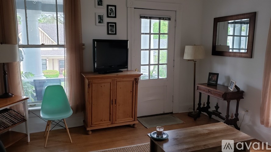 A living room with a green chair, a television, and a cabinet.