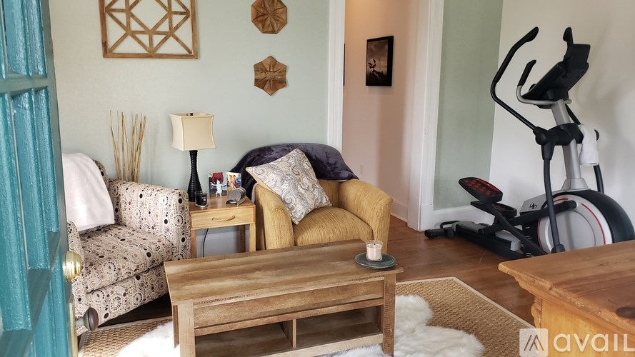A living room with a couch, a chair, a coffee table, and a bicycle.