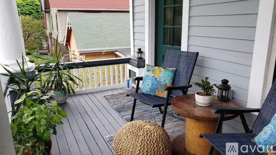 A porch with two chairs and a table with a plant on it.