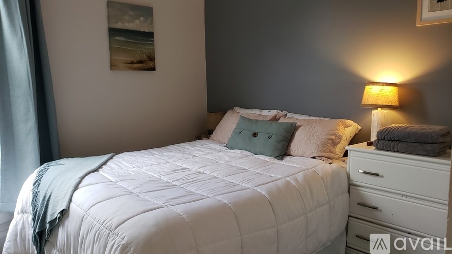 A bed with a white comforter and a blue pillow is in the image.
