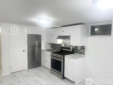 A kitchen with white cabinets and a stainless steel refrigerator.