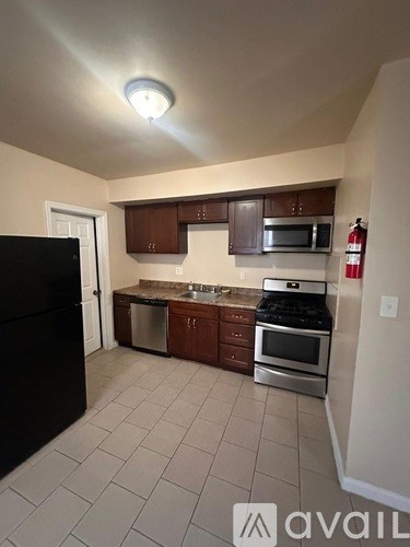 A kitchen with a black refrigerator, stainless steel oven, microwave, and cabinets.