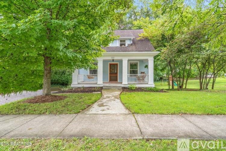 A white house with a brown door and a porch.