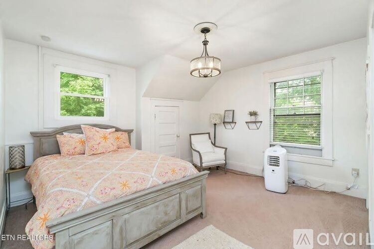 A bedroom with a large bed and a window with blinds.