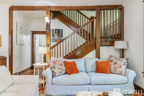 A living room with a white couch and a wooden staircase.