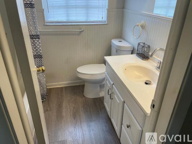 A bathroom with a toilet, sink, and a window.