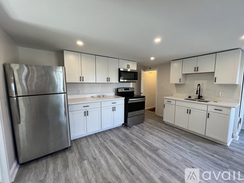 A kitchen with white cabinets and a stainless steel refrigerator.