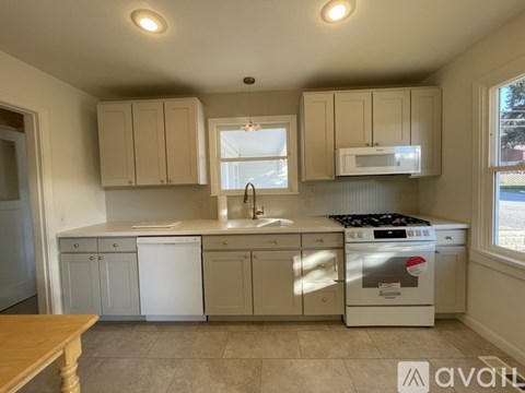 A kitchen with white appliances and cabinets.