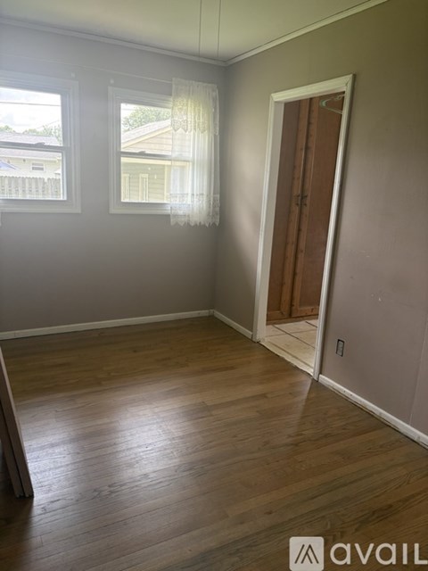 A room with wooden floors and a door leading to another room.