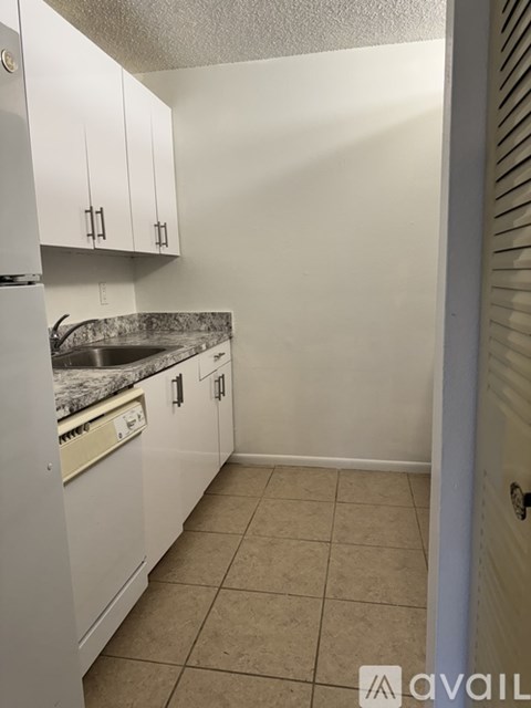 A kitchen with white cabinets and a marble countertop.