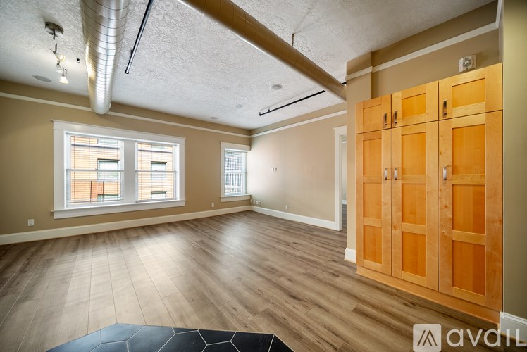 A spacious room with wooden floors and a large window.