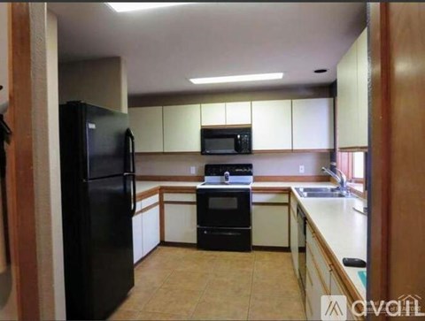 A kitchen with black appliances and white cabinets.