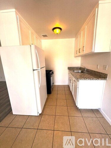 A kitchen with a white refrigerator and cabinets.