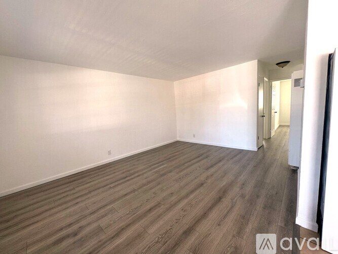 A room with wooden flooring and white walls.