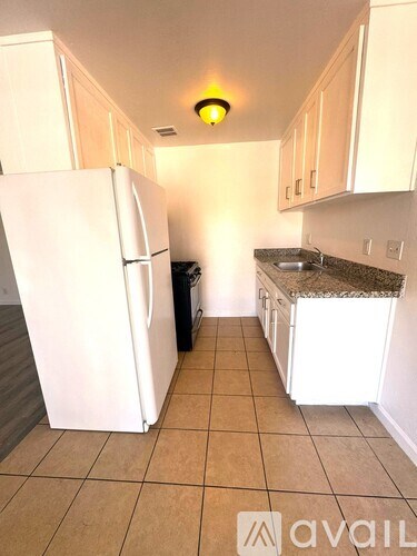 A kitchen with a white refrigerator and cabinets.