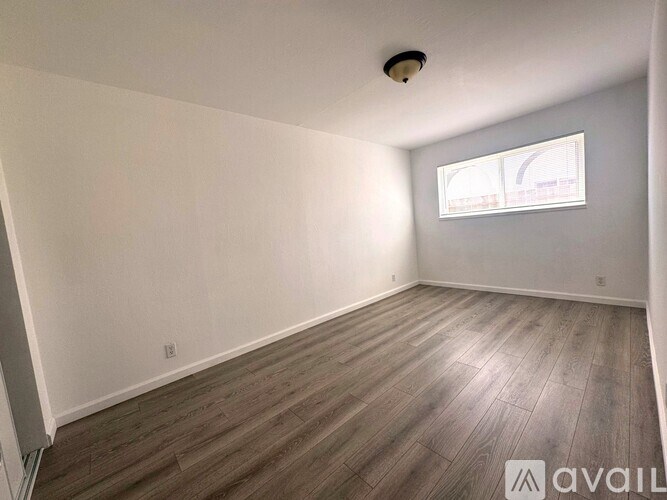 A room with wooden flooring and a window.
