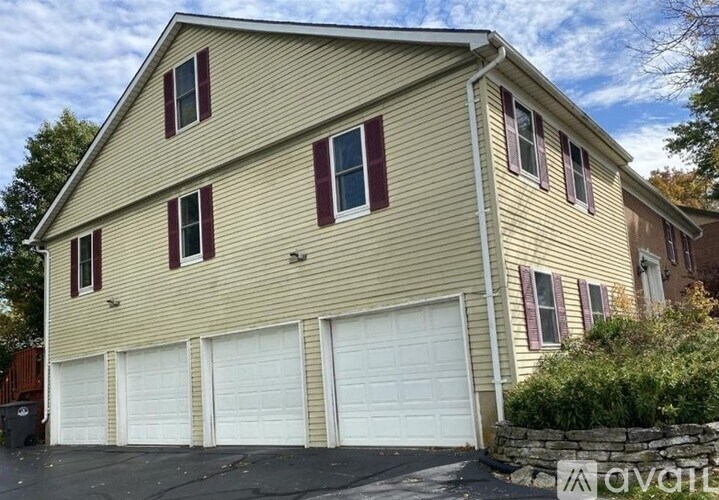 A two-story house with a garage and a stone wall.