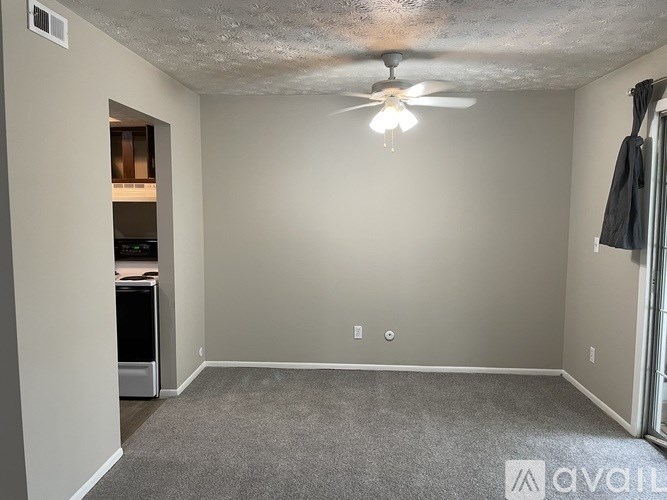 A room with a ceiling fan and a carpeted floor.