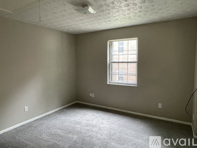 A room with a window and carpeted floor.