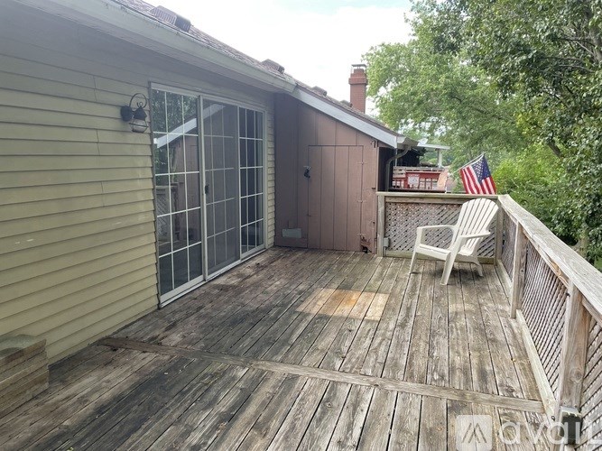 A wooden deck with a sliding glass door and a white chair.