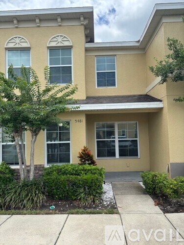 A two-story house with a front yard and a tree.
