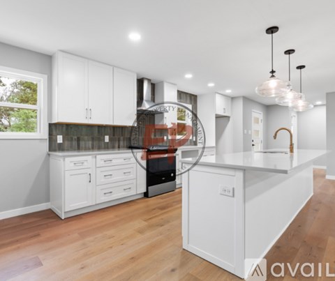 A modern kitchen with white cabinets and a wooden floor.