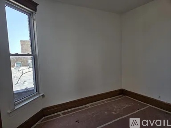A room with a window and a view of a street and buildings outside.