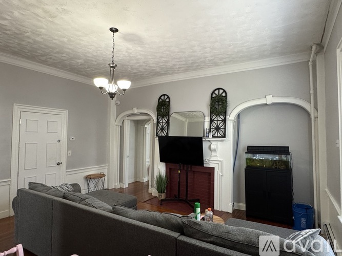 A living room with a grey couch and a chandelier.