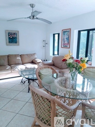 A living room with a glass table and wicker chairs.