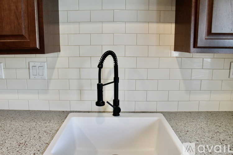 A black kitchen faucet is installed in a white sink.