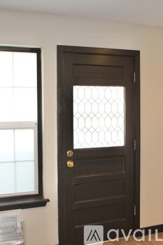 A brown door with a glass panel and gold knobs.