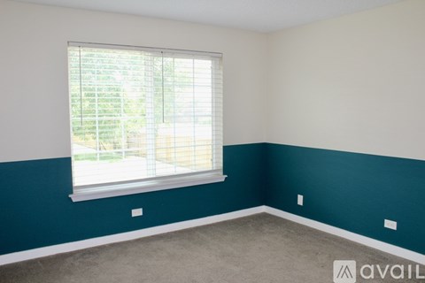 A room with a window and a view of a fence and trees outside.